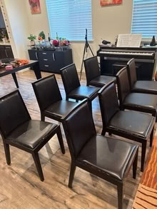Photo of free 8 black dining chairs- has wear and tear on seat, no structural damage #1